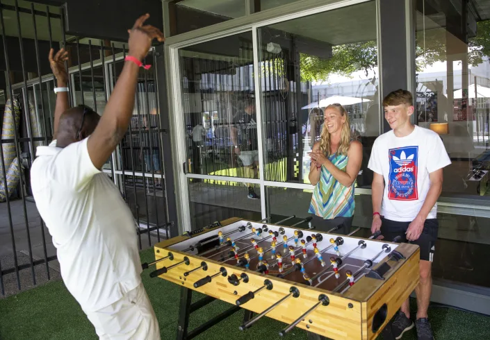 Joseph Codrington, left, plays foosball with Melissa Mattox and her son Elijah at a fraternity house