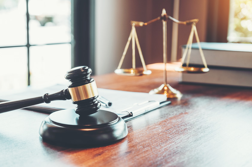 gavel and a scale on a desk with books in a room with windows