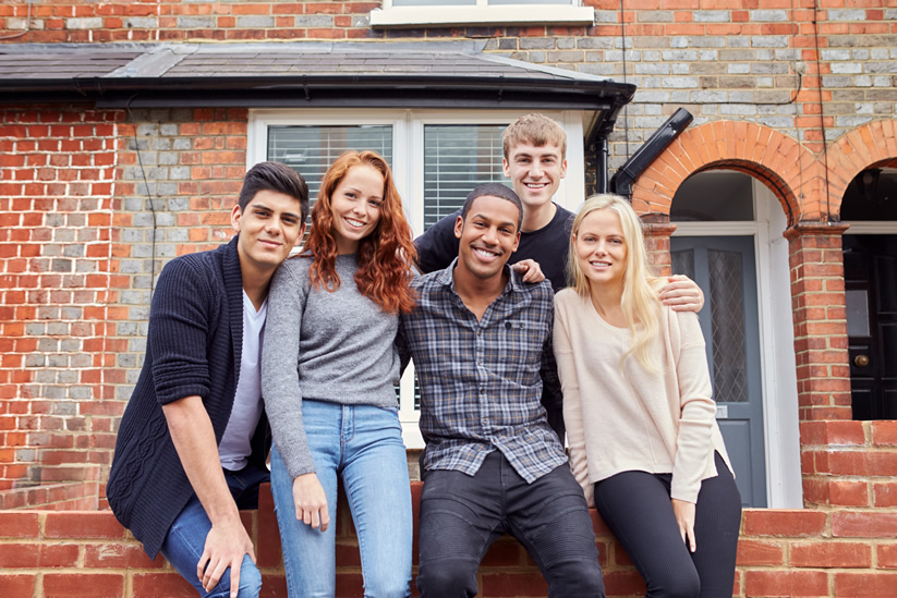 College students sitting outside off-campus house